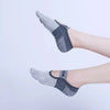 A close-up of a person's foot wearing gray silicone yoga and fitness socks.