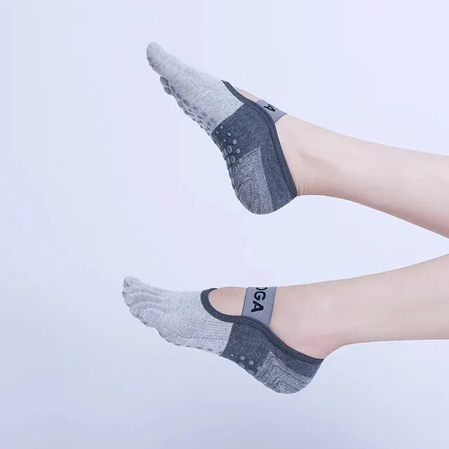 A close-up of a person's foot wearing gray silicone yoga and fitness socks.