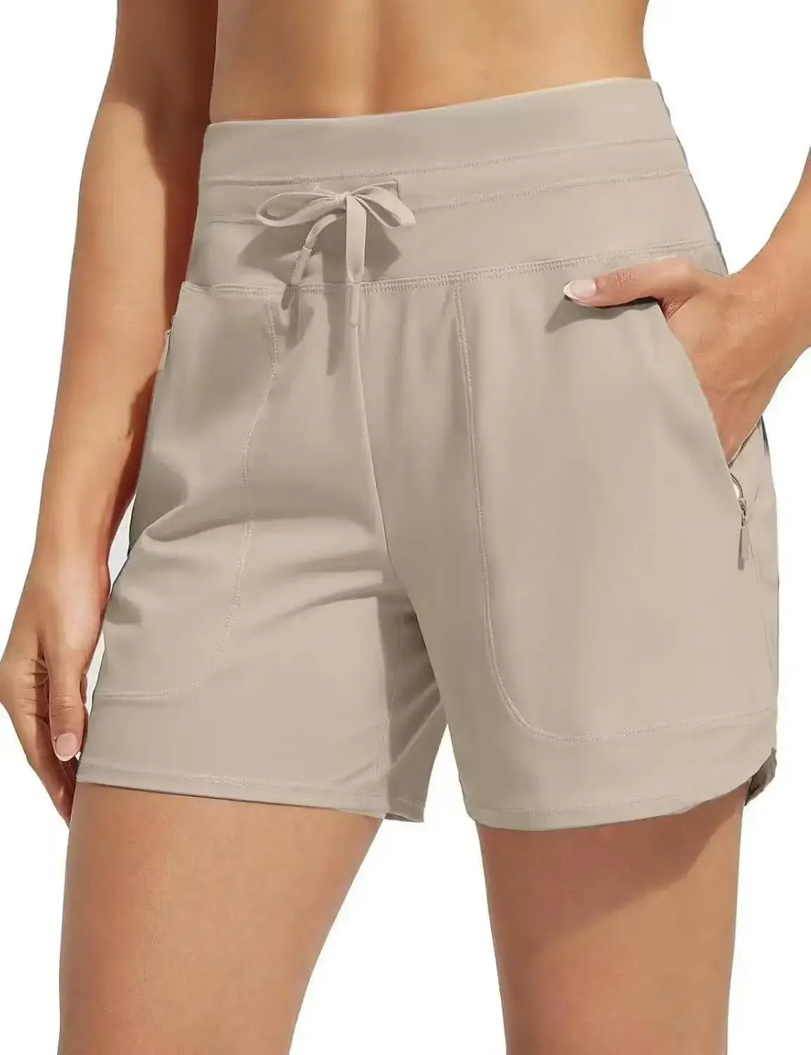 Light beige high-waisted quick-dry athletic shorts worn by a woman.