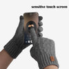 A hand wearing a gray knit glove is touching a sensitive touch screen on a smartphone.