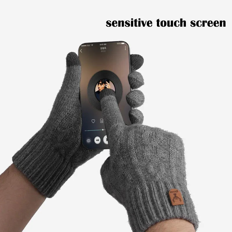 A hand wearing a gray knit glove is touching a sensitive touch screen on a smartphone.