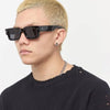 A close-up of a man wearing black Rivet Anti-Light sunglasses and a black shirt.