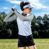 Eine Frau mit weißen Ärmelblusen und einem Visor schwungt einen Golfschläger im Freien.