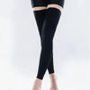 A person wearing black medical compression stockings on their legs.