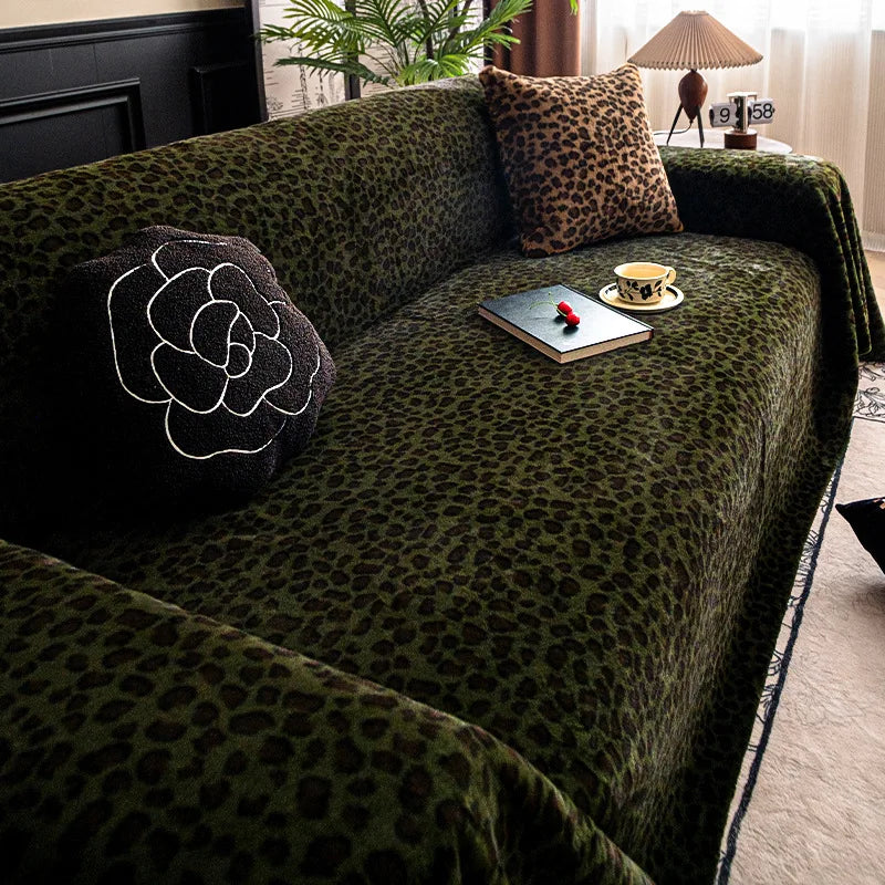 A dark green plush sofa cover blanket with a leopard print pattern, featuring decorative pillows and a small tray.