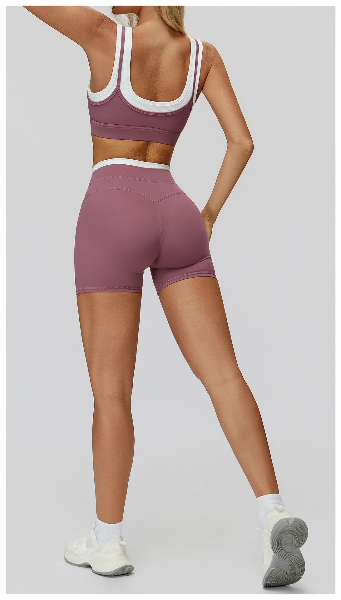 Eine Frau modelliert ein mauvefarbenes Yoga- und Trainingsanzug-Set mit Crop-Top und passenden Shorts.
