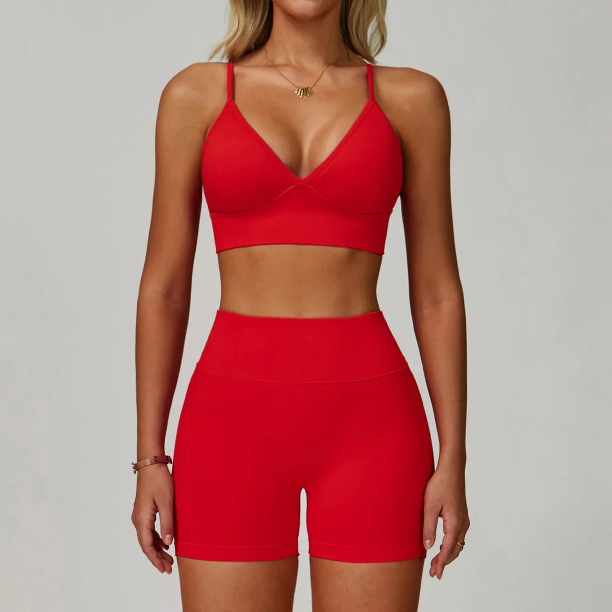 Eine Frau modelliert ein rotes, nahtloses Sport-Yoga-Set mit Crop-Top und passenden Shorts.