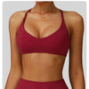 A woman models a maroon yoga fitness sports bra and matching bottoms.