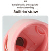 A close-up view of a pink insulated water bottle with a built-in straw feature.
