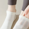 Une paire de chaussettes de yoga et de fitness blanches respirantes portées sur le pied et la cheville d'une personne.