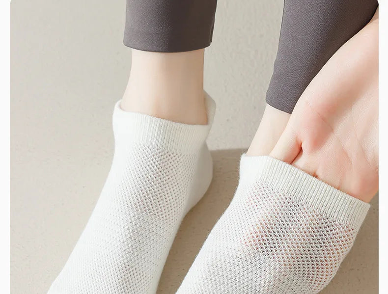 Une paire de chaussettes de yoga et de fitness blanches respirantes portées sur le pied et la cheville d'une personne.