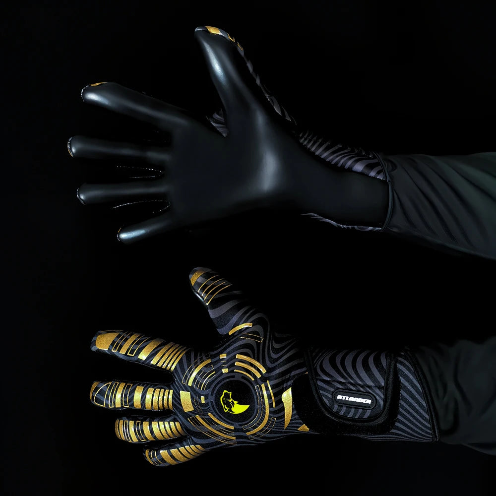 A hand wearing black and gold high-performance goalkeeper gloves is extended against a dark background.