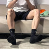 A person wearing black socks is sitting on a couch, with white shirt and dark shorts visible.