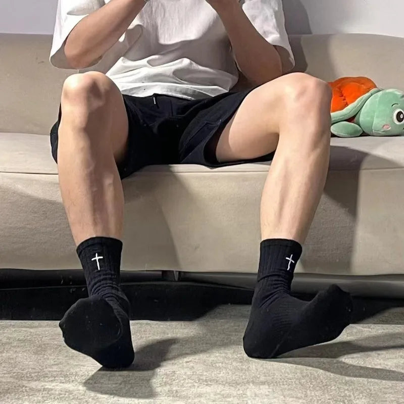 A person wearing black socks is sitting on a couch, with white shirt and dark shorts visible.