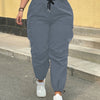 A person wearing gray high-waist drawstring cargo joggers standing outdoors on steps.