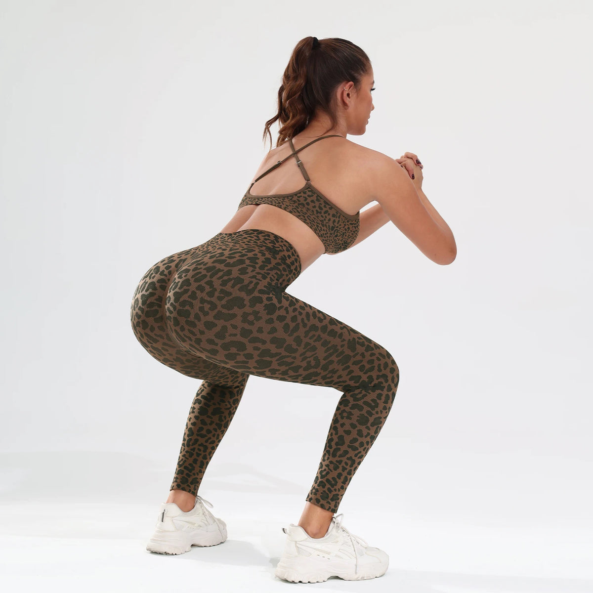 A woman models a leopard print seamless two-piece sports set in olive green against a white background.