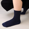A close-up of a navy blue bamboo fibre anti-odor sock being worn on a person's ankle and foot.