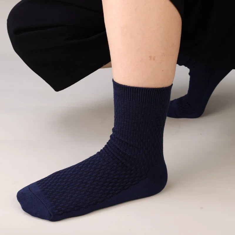 A close-up of a navy blue bamboo fibre anti-odor sock being worn on a person's ankle and foot.