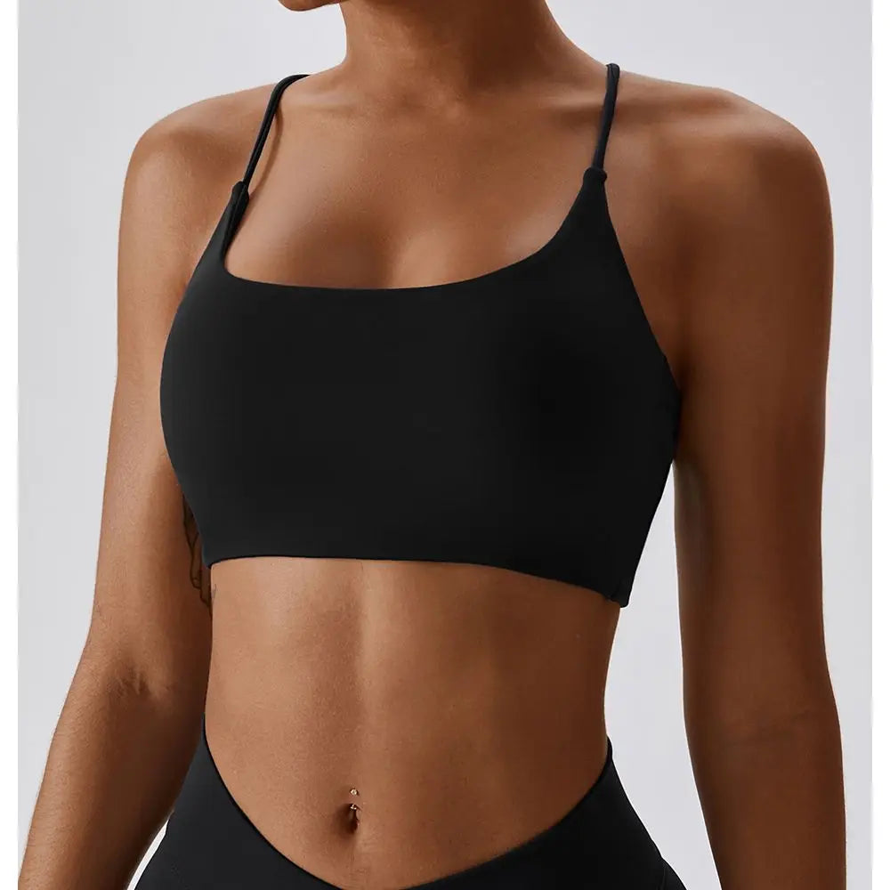 Una mujer vistiendo un sujetador deportivo en forma de U negro para fitness y yoga.