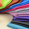 A stack of colorful microfiber cooling towels in various shades of pink, purple, blue, and black on a wooden surface.