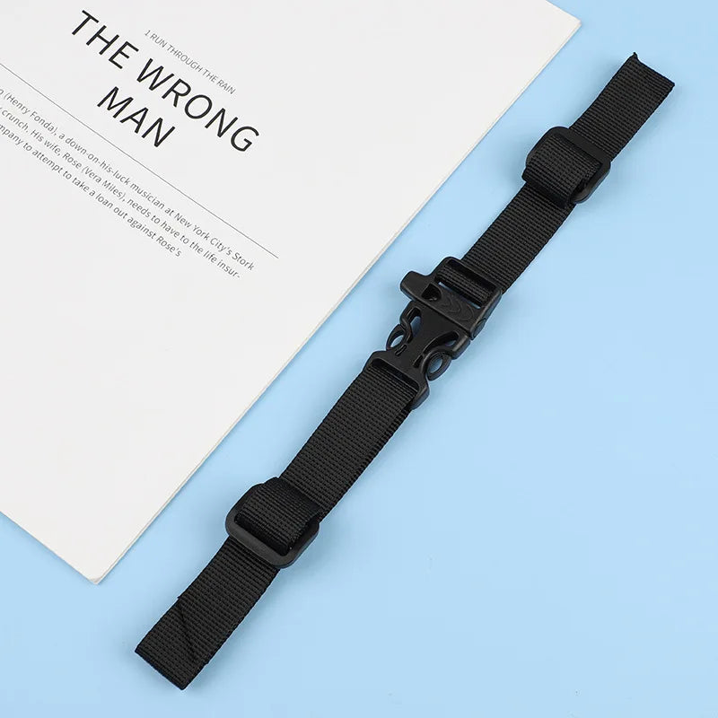 A black adjustable tactical backpack strap harness lying on a light blue surface next to a document.