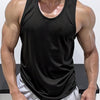 A muscular man wearing a black sleeveless tank top and light gray athletic shorts.
