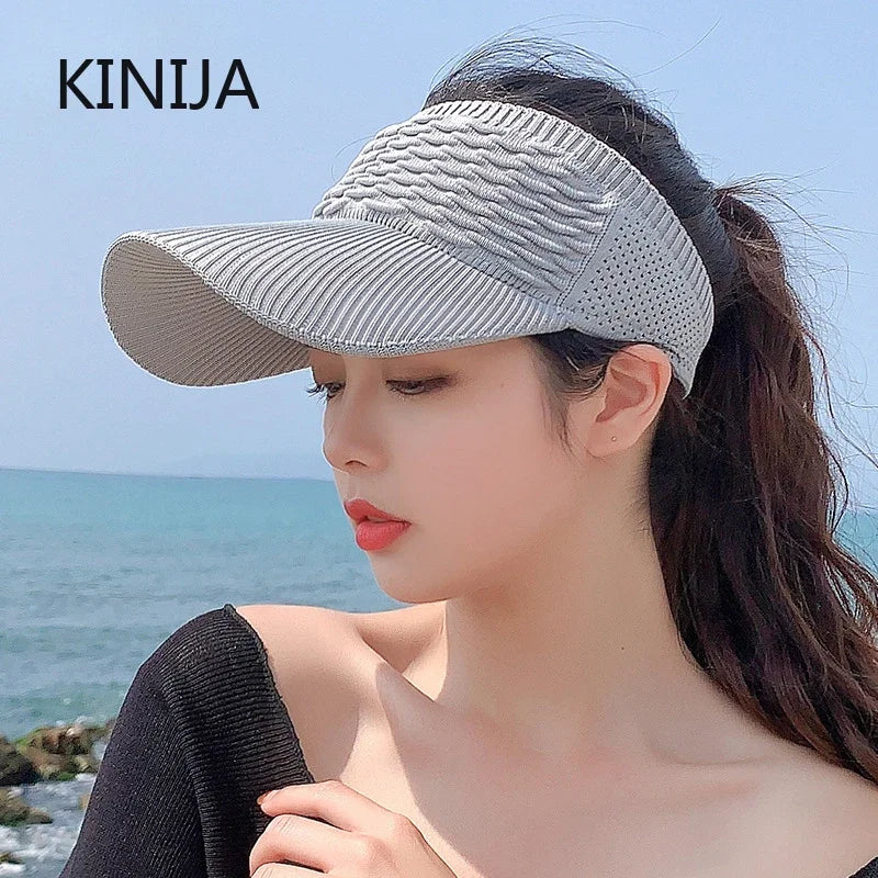 A woman wearing a grey breathable anti-UV adjustable sun hat outdoors near the sea.