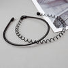 Black coiled metal hair bands laid on a light gray surface next to a piece of paper.