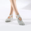 Gray breathable silicone yoga and pilates socks worn on a person's feet.
