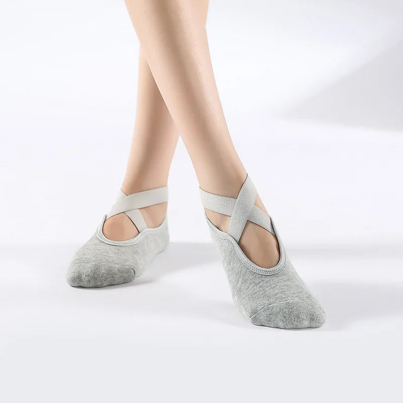 Gray breathable silicone yoga and pilates socks worn on a person's feet.