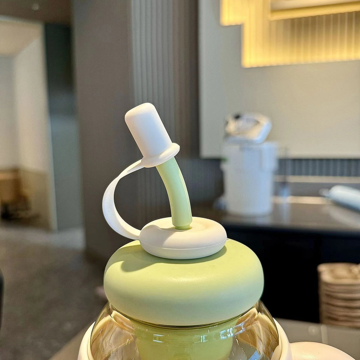 A reusable leak-proof water bottle with a straw and handle, featuring a light green lid and white accents.