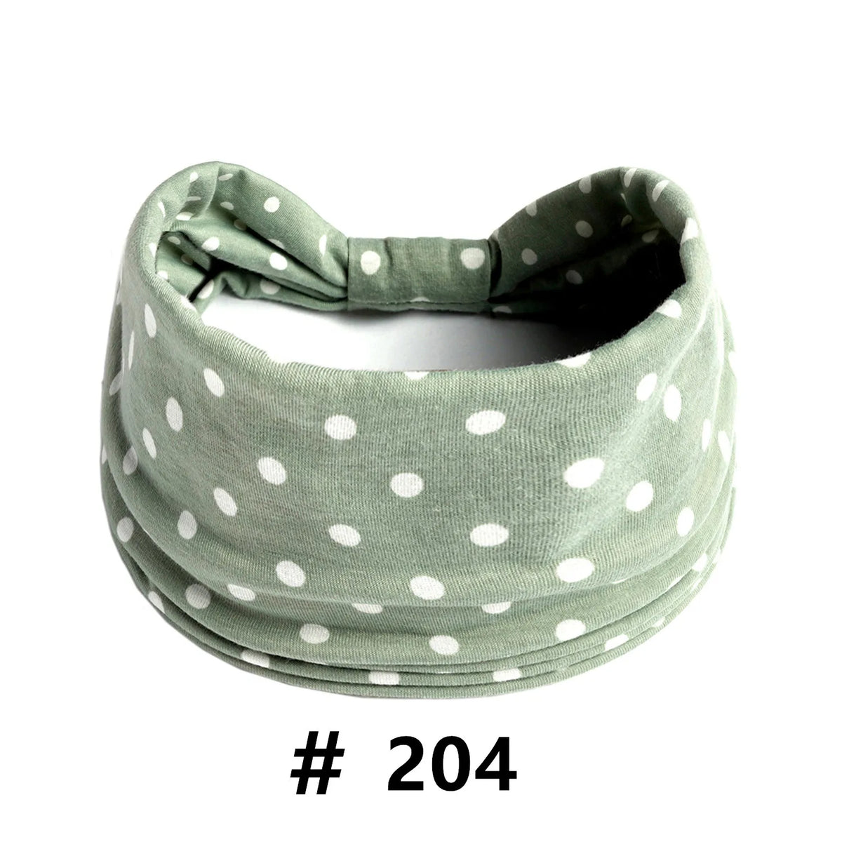 A soft sage green knitted headband with white polka dots, shown flat.