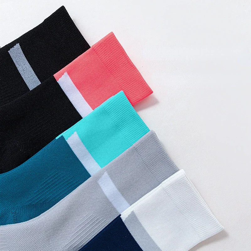 A stack of colorful performance athletic running socks in black, pink, teal, and gray.