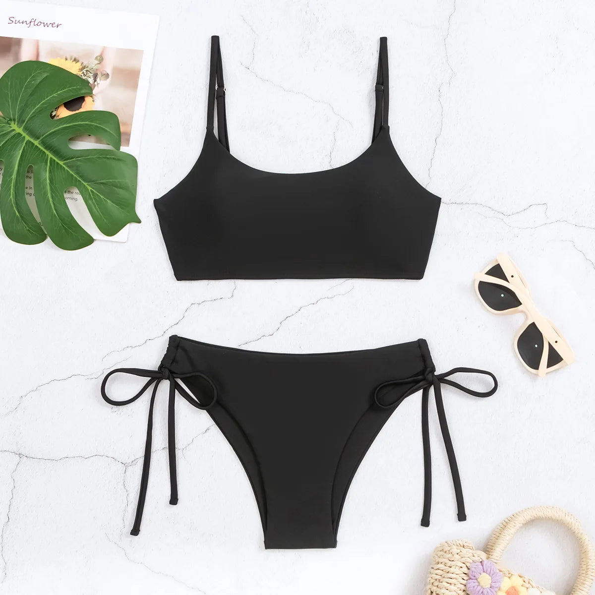 Schwarzes String-Bikini-Set mit hoher Taille für Damen, auf einer weißen Oberfläche präsentiert.