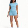A woman models a light blue two-piece workout set consisting of a short-sleeved top and matching shorts.