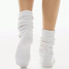 A pair of white slouch knit scrunch socks worn on a person's foot.