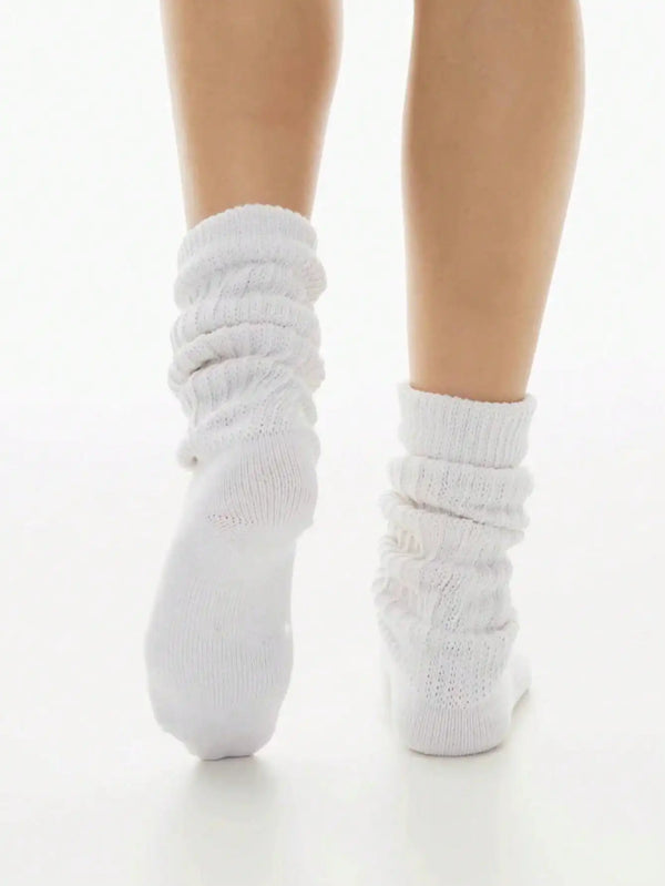 A pair of white slouch knit scrunch socks worn on a person's foot.