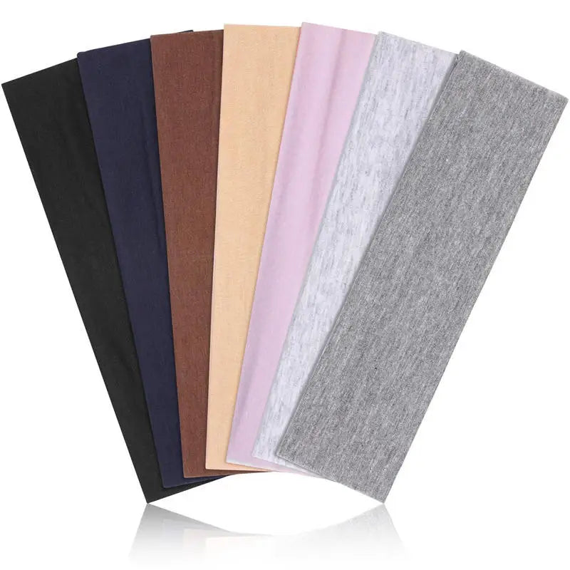 A collection of nine stretchy multi-color sports headbands displayed in a row.