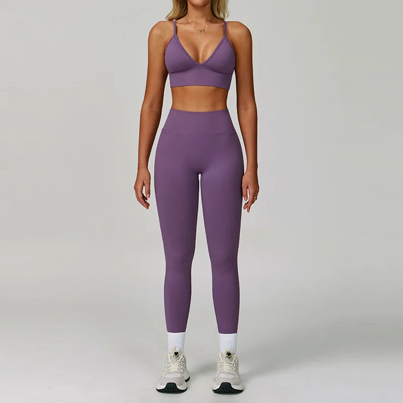 Eine Frau modelliert ein nahtloses Sport-Yoga-Set in Lila mit Crop-Top und langen Leggings.