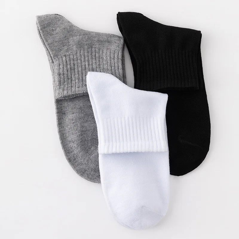 A set of three men's mid-calf cotton socks in gray, black, and white.