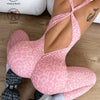 A woman wearing a pink leopard print seamless yoga jumpsuit and athletic shoes, viewed from the back.