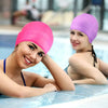 A woman wearing a bright pink silicone swimming cap is relaxing in a pool.