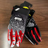 A pair of black and white durable riding gloves with red accents are displayed on a wooden surface.