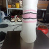 A close-up of a white sock with horizontal pink and black stripes, displayed on a dark surface.
