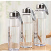 Tres botellas de agua de vidrio transparente con tapas de silicona gris sobre una superficie de madera.