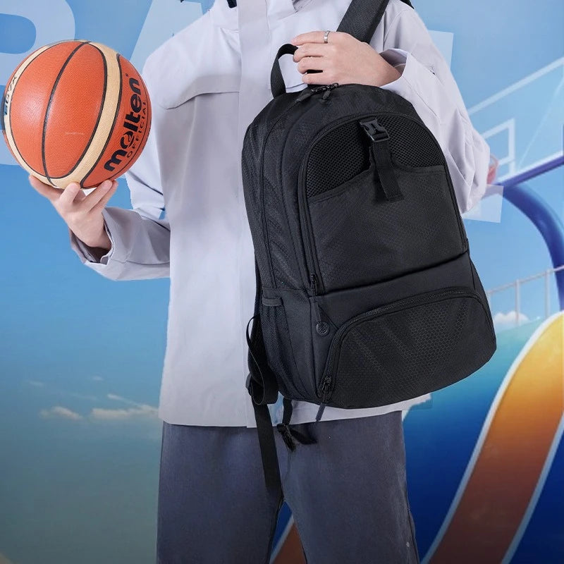A person wearing a white shirt and dark pants is holding an orange basketball and carrying a black multi-sport fitness backpa