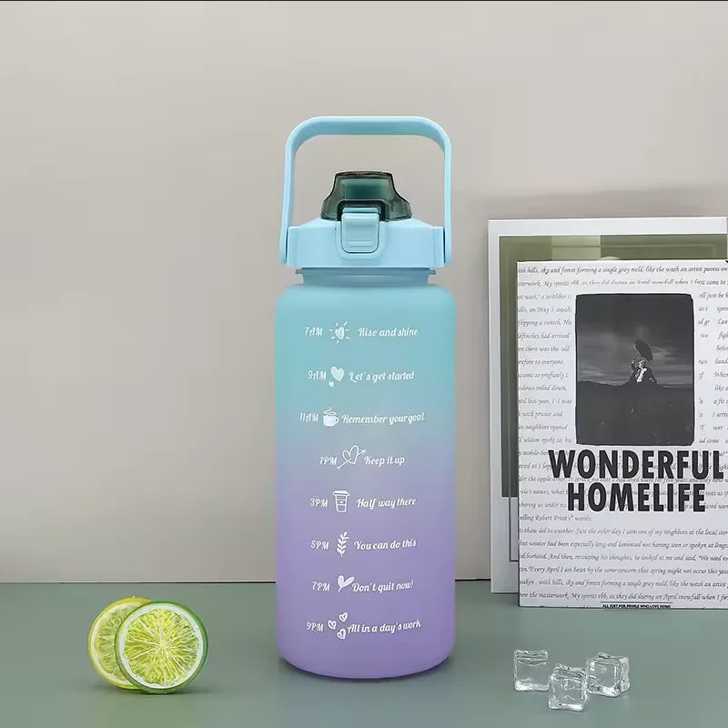 A light blue sports water bottle with a straw and motivational text printed on it, next to sliced lime.