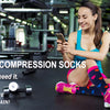 A woman is sitting on the floor smiling while holding a smartphone, with funny compression socks visible nearby.