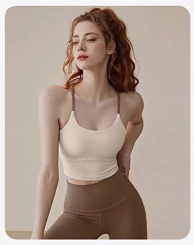 A woman wearing a beige supportive sports bra and matching leggings posing for a studio photo.