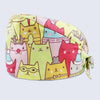 A yellow fabric surgical cap printed with various cute cat faces in pink, orange, and green.